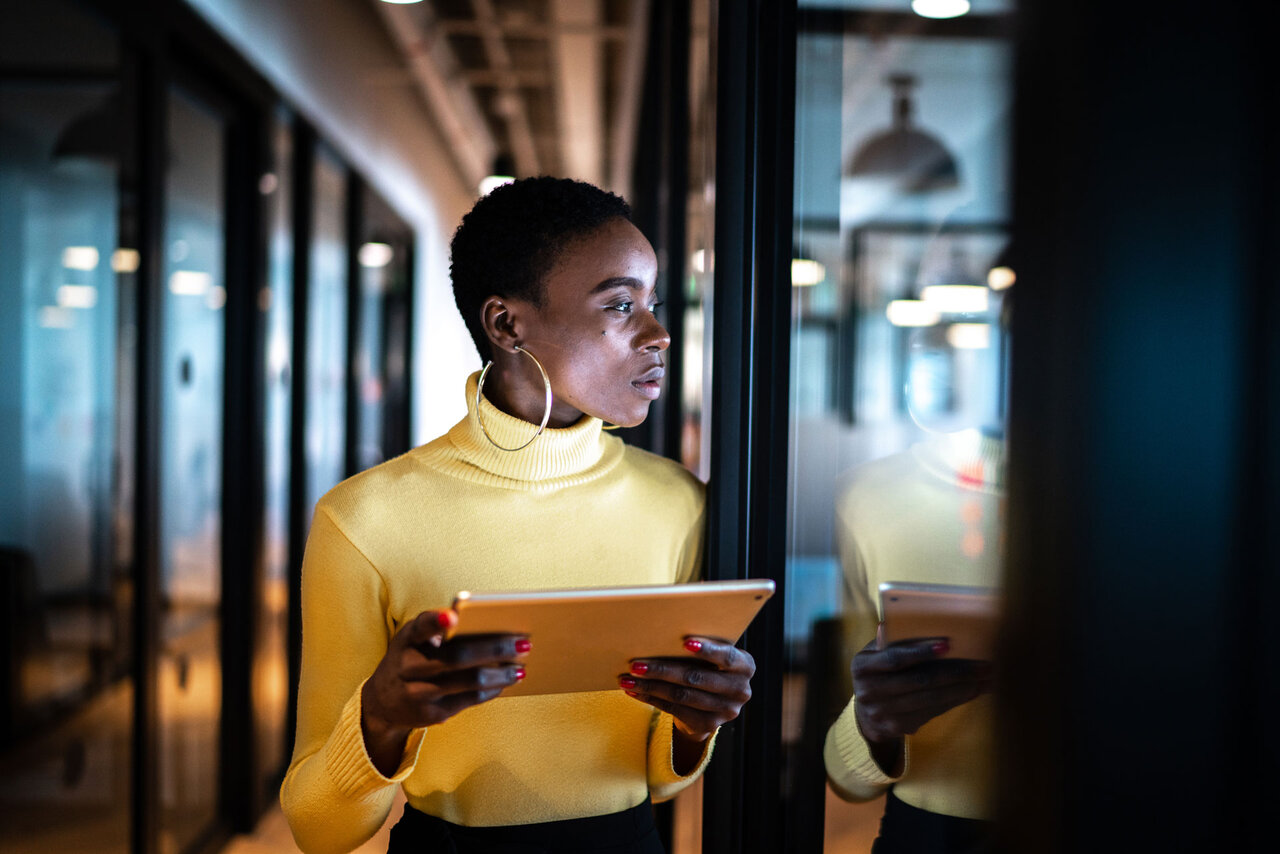 Young business woman using digital tablet and looking away in an office | © GettyImages