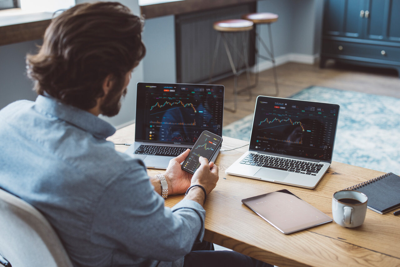 Businessman working from home. Using laptops. Trading stock or cryptocurrencies. Trading app on screen. | © GettyImages