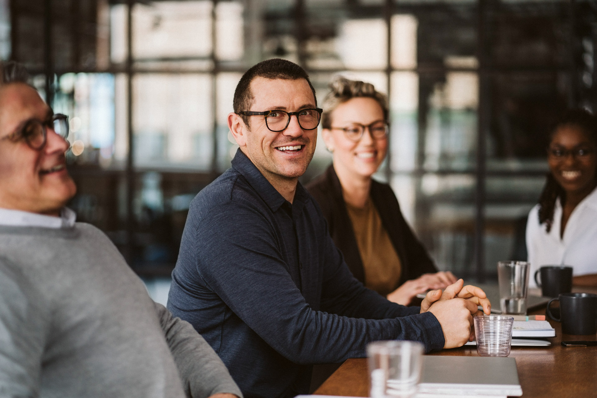 Laughing businessmen sitting around a table | © Maskot @Getty